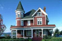 трехэтажный деревянный дом с фасадами кирпичного цвета с башней на углу